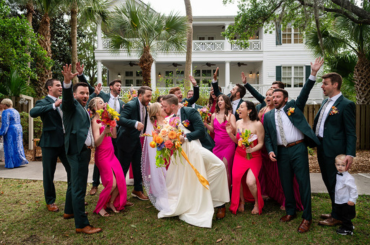 bridal party celebrating and couple kissing